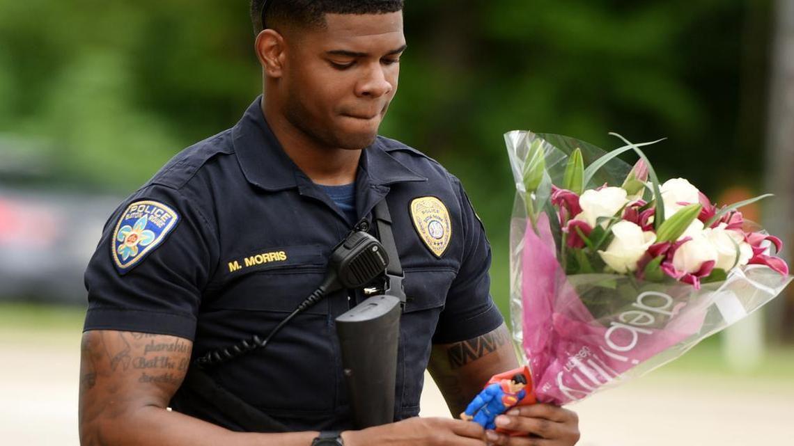 Baton Rouge Police Department Officer Markell Morris holds a bouquet of flowers and a Superman action figure that a citizen left at the Our Lady of the Lake Hospital where the police officers were brought this morning, Sunday, July 17, 2016. Multiple law enforcement officers were killed and wounded Sunday morning in a shooting near a gas station in Baton Rouge.