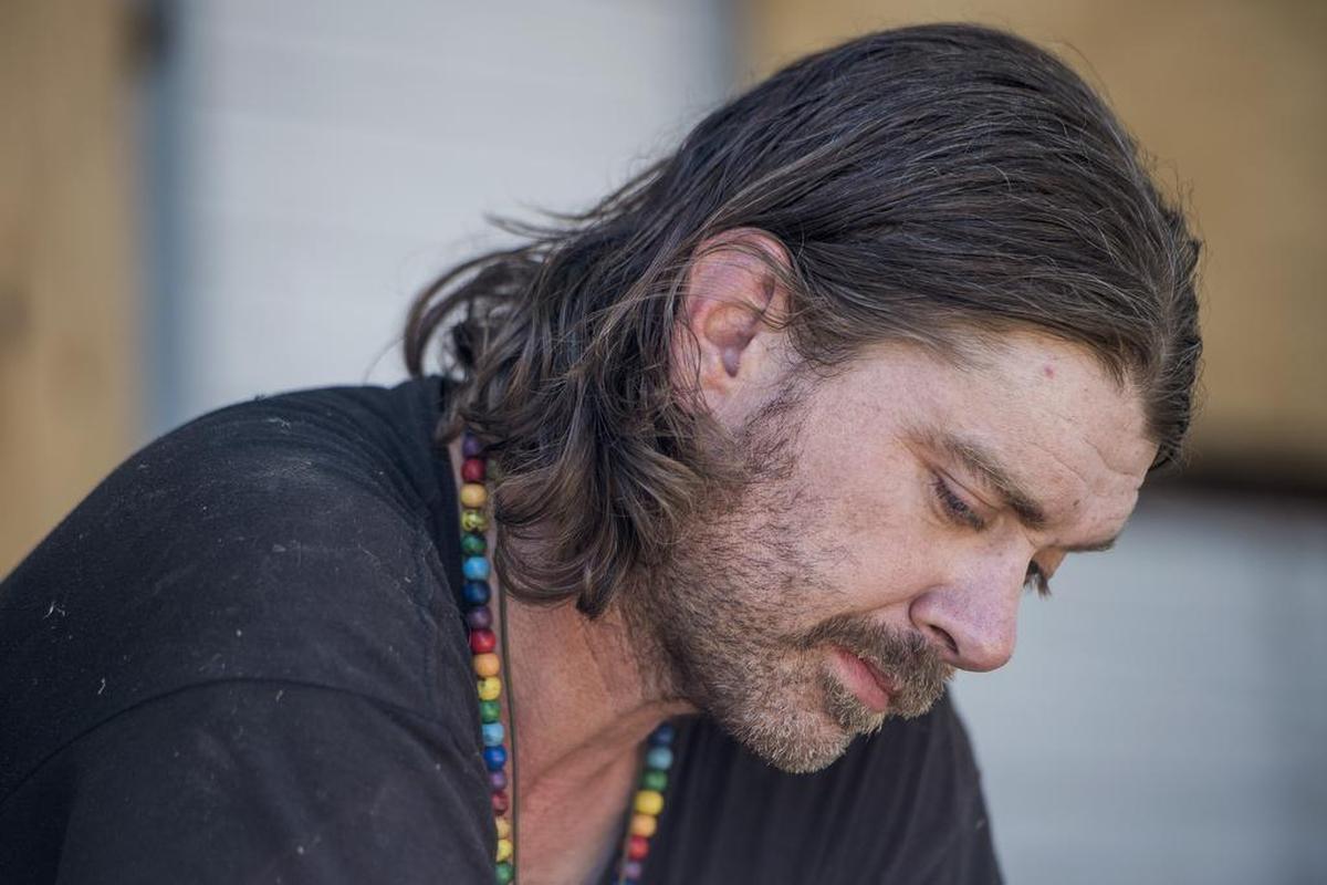 Thomas Mullen looks down on the front porch of the abandoned home he's staying in on Truckee Way off 34th Street on Wednesday July 19, 2017, in Sacramento, Calif. Mullen's has been staying there since July 12, when Caltrans impounded his "pod" home. Thomas' father, Jim, built the pod for his son.