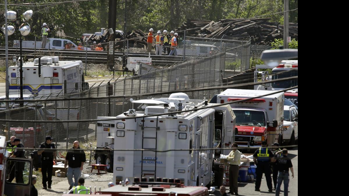 
Investigators, center back, stand on the tracks near Tuesday's deadly train derailment, Thursday, May 14, 2015, in Philadelphia. An Amtrak train headed to New York City derailed and crashed in Philadelphia on Tuesday night killing eight people and sending more than 200 passengers and crew to area hospitals. 

