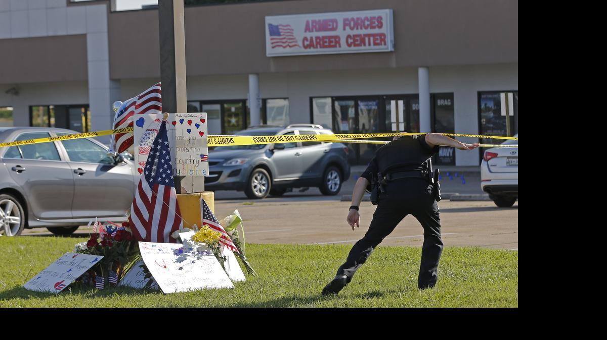 
A police officer ducks under tape near a memorial in front of an Armed Forces Career Center on Thursday, July 16, 2015, in Chattanooga, Tenn. A gunman unleashed a barrage of fire at the center and another U.S. military site a few miles apart in Chattanooga, killing several and sending service members scrambling for cover as bullets smashed through the windows. The attacker was also killed.
