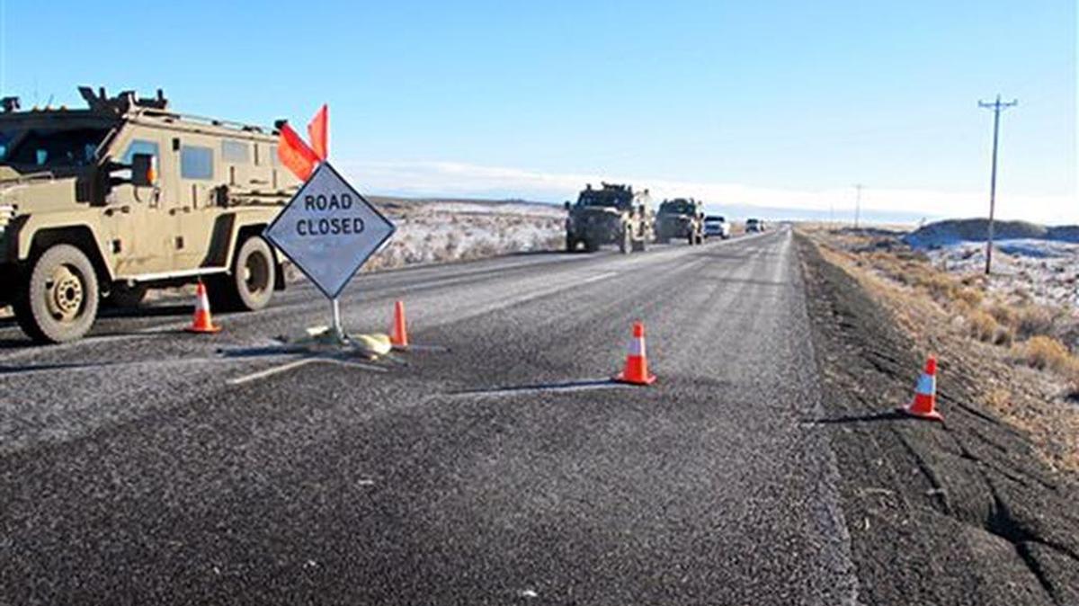 A convoy of armored vehicles and SUVs rolls past a barricade on the road near the Malheur National Wildlife Refuge near Burns, Ore., Saturday, Jan. 30, 2016. The remnants of an armed group occupying the refuge to protest federal land policies say they won't leave until they get assurances they won't be arrested.