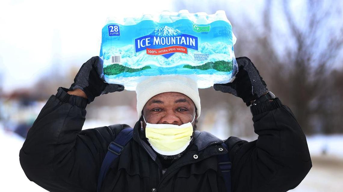 Carl Huntere, 48, of Flint, Mich., walks home through the snow from the North End Soup Kitchen in Flint on Wednesday, Jan. 13, 2016, where he received a case of free bottled water.
