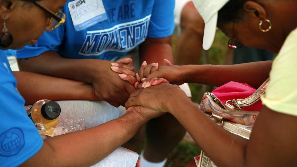 Mercedes Harris, izquierda, Teresa Reed, centro, y Corliss Wade rezan juntas en una reunión de la comunidad en Ferguson, Missouri, el 25 de julio de 2015. 