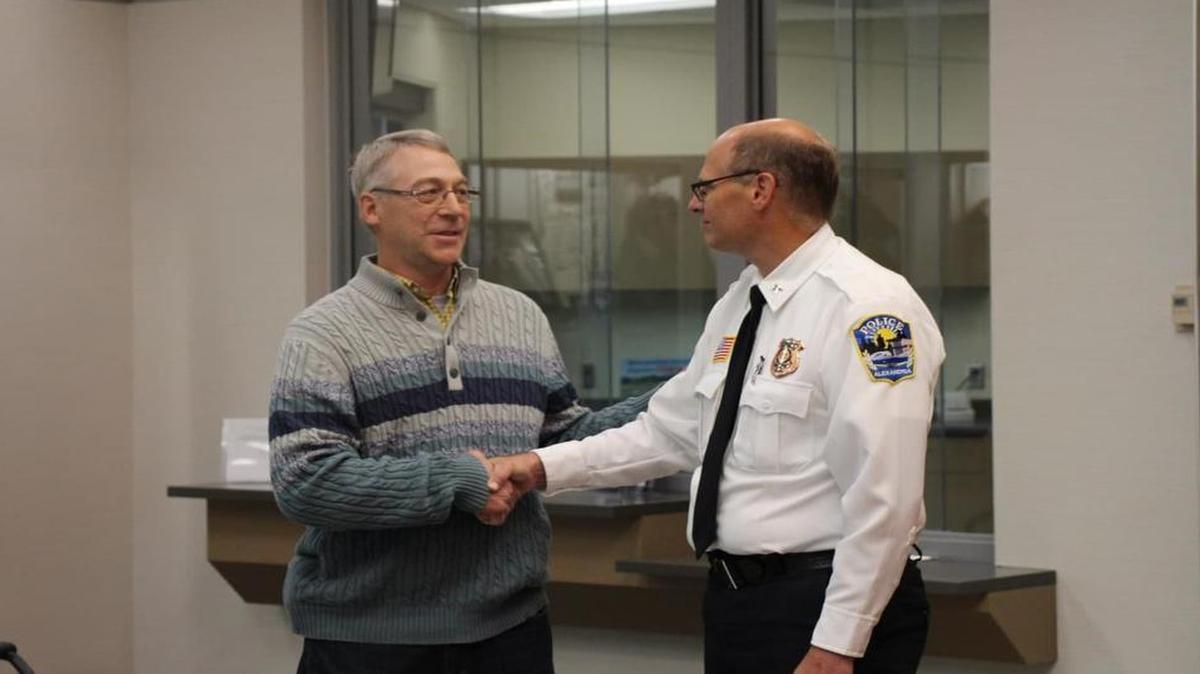 Earl Melchert, left, shakes hands with Alexandria, Minneosta, Police Chief Richard Wyffels on Friday as they both presented a reward to the family of a kidnapped girl who escaped captivity after 29 days.