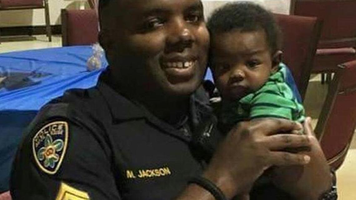Baton Rouge Police Officer Montrell Jackson, holds his son Mason at a Father's Day event for police officers in Baton Rouge, La. Montrell Jackson and two other Baton Rouge law enforcement officers investigating a report of a man with an assault rifle were killed Sunday, less than two weeks after a black man was fatally shot by police here in a confrontation that sparked nightly protests that reverberated nationwide.