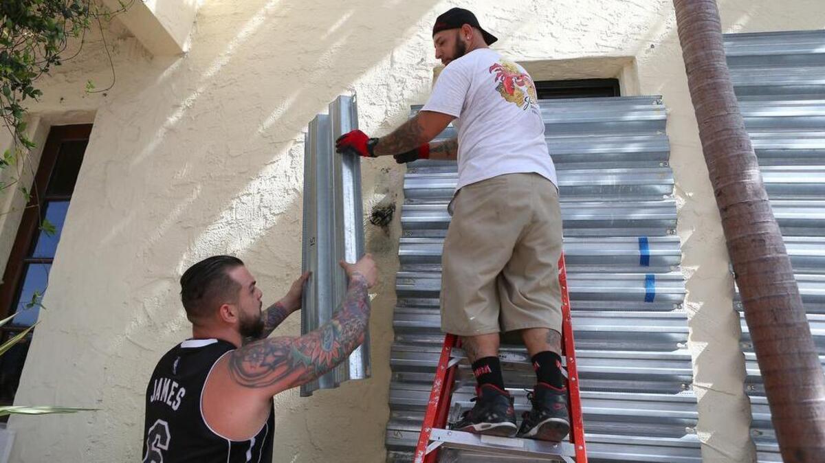 
From left to right, Employees from Joe’s Stone Crab Jordan Garcia and Manny Cortes installing shuttles in preparation for Tropical Storm Erika , Friday August 28, 2015 in Miami Beach.
