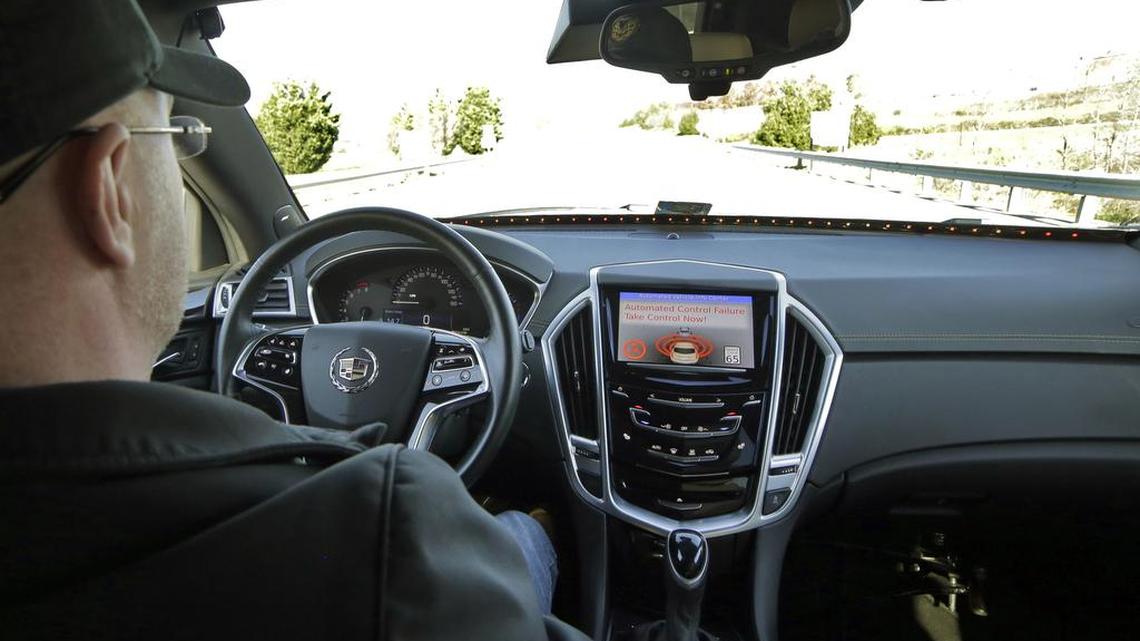 This photo provided by Virginia Tech shows Virginia Tech Center for Technology Development Program Administration Specialist Greg Brown behind the wheel of a self-driving car during a test ride showing the alert system handing over automation to the driver while traveling street in Blacksburg, Va.