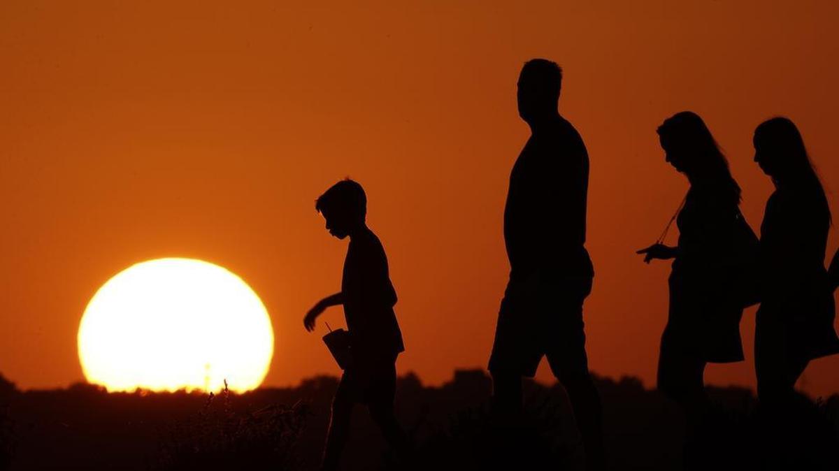 In this July 21, 2016, file photo, The sun sets beyond visitors to Liberty Memorial as the temperature hovers around 100 degrees in Kansas City, Missouri, on July 21, 2016.