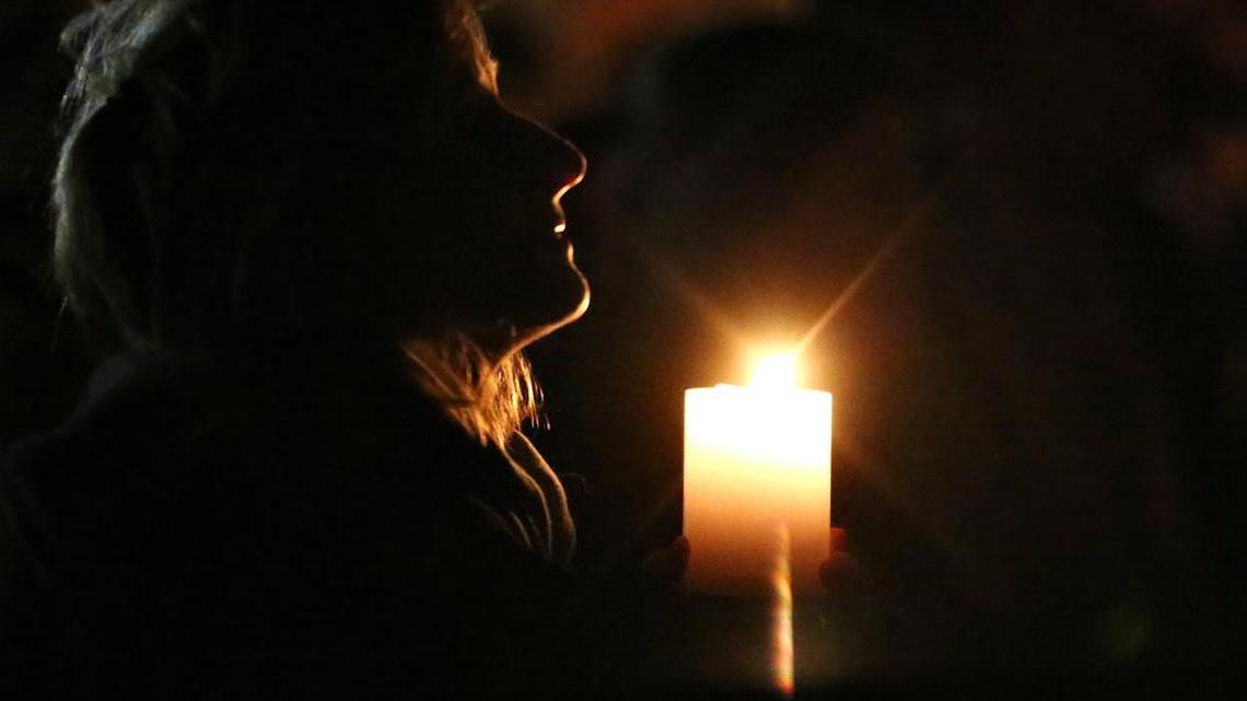 A vigil attendee holds a candle Tuesday on the soccer field of Mattawan High School in Mattawan, Mich., to honor Tyler and Richard Smith, two of the victims of a shooting. Jason Dalton admitted to gunning down randomly chosen victims in and around Kalamazoo, Mich., on Saturday.