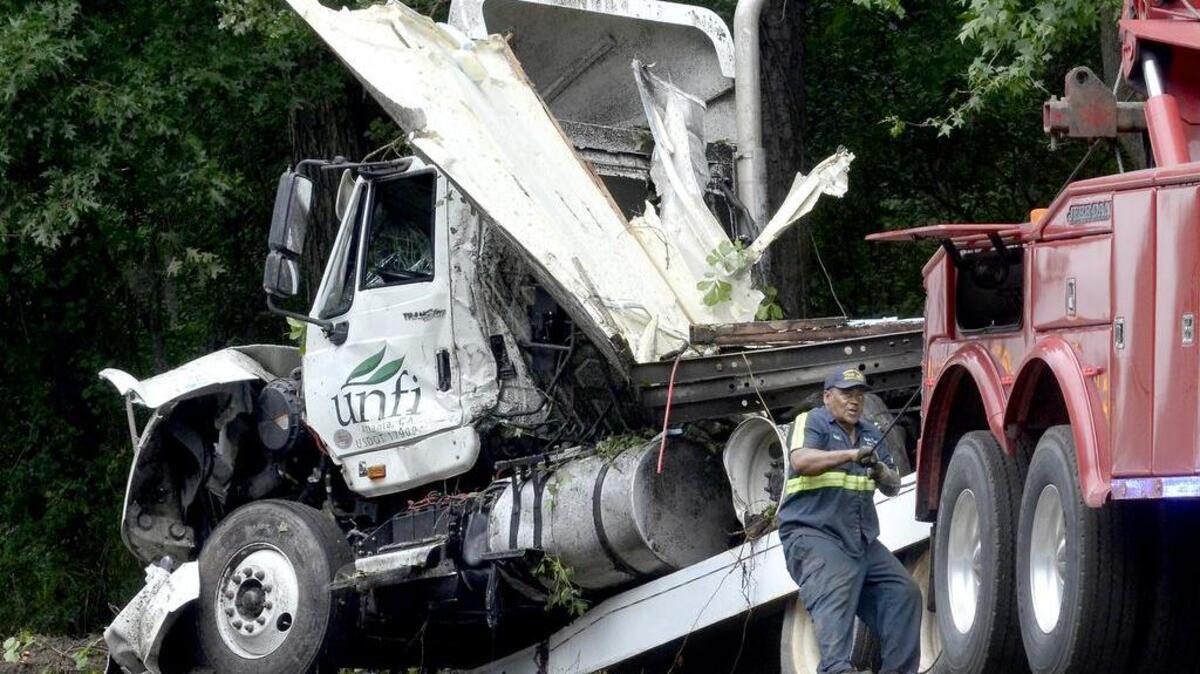 A worker loads a severely damaged semi cab onto the flatbed of his truck, after an eight-vehicle wreck in South Carolina that started after a tractor trailer on Interstate 95 hydroplaned and hit a tree, causing the tree to fall into the roadway.