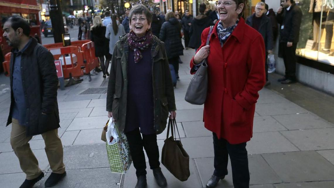 Hazel Newton, center left, poses for a picture with her sister as they walk down Oxford Street, in London, Dec. 9, 2015. There’s good news the grumpy among us: Being happy apparently has no effect on how long you might live.