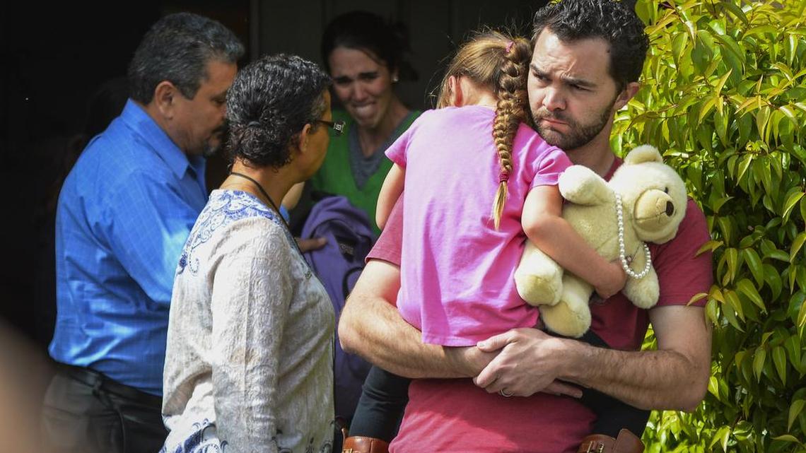 Rusty Page carries Lexi while Summer Page, in the background, cries as members of family services, left, arrive to take Lexi away from her foster family in Santa Clarita, Calif., on Monday. Lexi, who spent most of her life with California foster parents, was removed from her home on Monday under a court order that concluded her native American blood requires her placement with relatives in Utah.