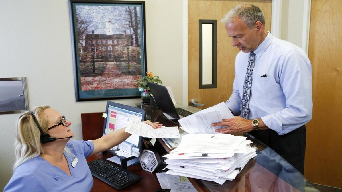 Dr. Richard Radnovich and administrative assistant Lindsay Beacham talk next to patient history files waiting to be sent to insurance companies.