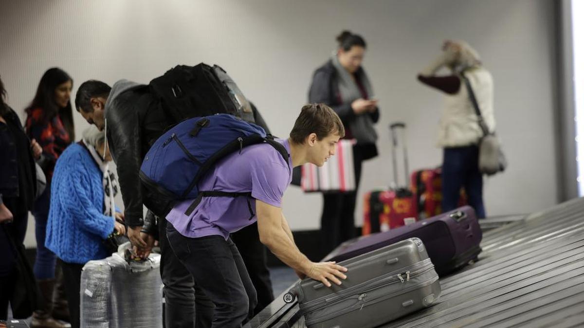 A traveler gathers his luggage at the San Francisco International Airport Sunday in San Francisco. About 3.6 million people tell the American Automobile Association they intend to fly this holiday week.