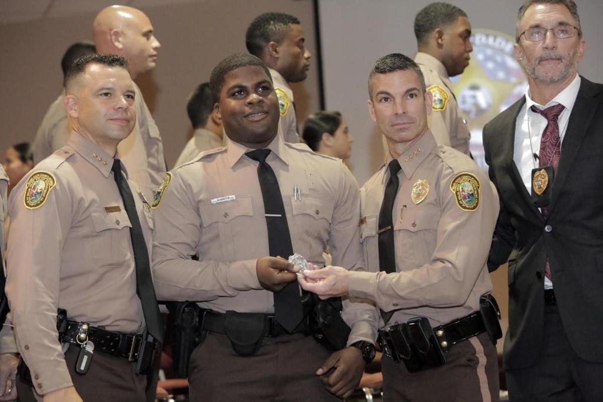 Andre Martin, second from left, receives his shield from Miami-Dade Police Director, Juan Perez. Also in the picture are Assistant Director of Police Alfredo Ramirez (left), and Lieutenant Bill Hellman, Miami-Dade Police, retired (right). Thursday morning, Andre Martin, a 26-year-old martial arts expert with a fiance and a child, was part of the new graduating class of Miami-Dade police.