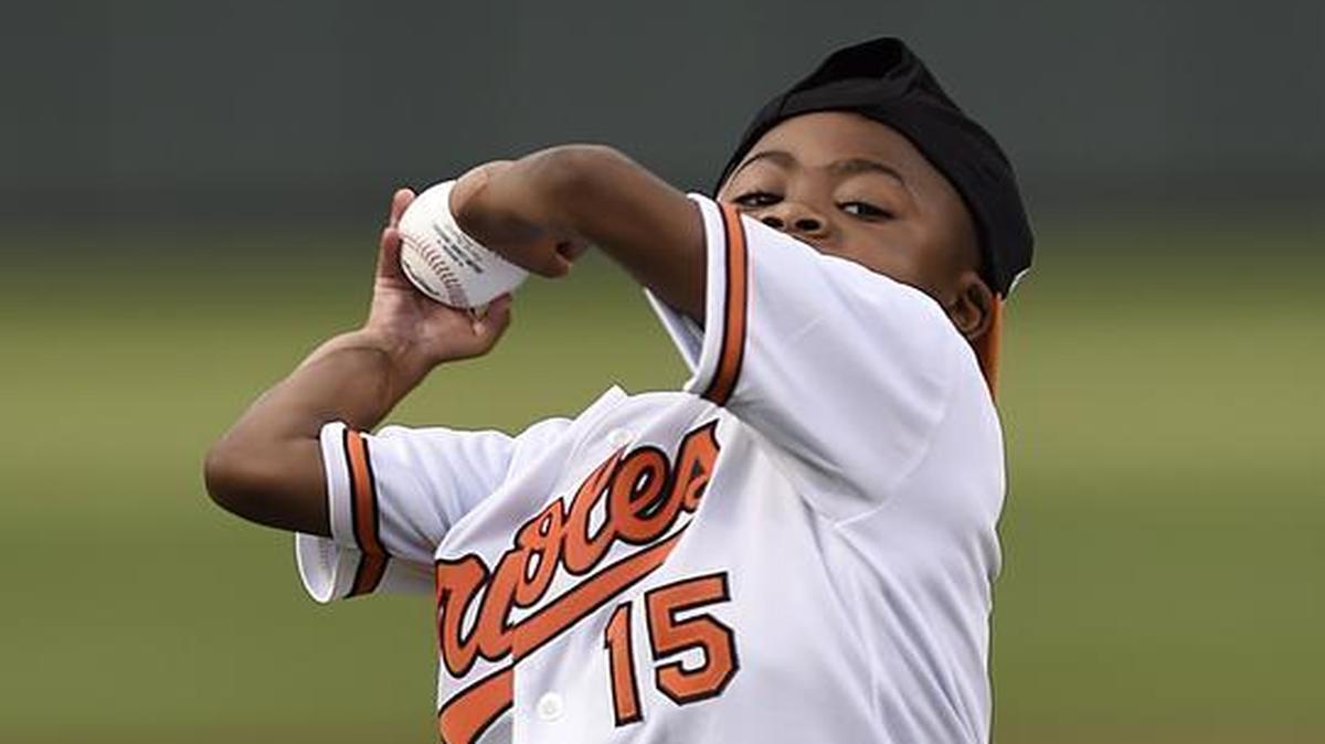 Zion Harvey, the world’s first child to receive a bilateral hand transplant, throws out the first pitch before the Baltimore Orioles and Texas Rangers baseball in Baltimore on Tuesday.