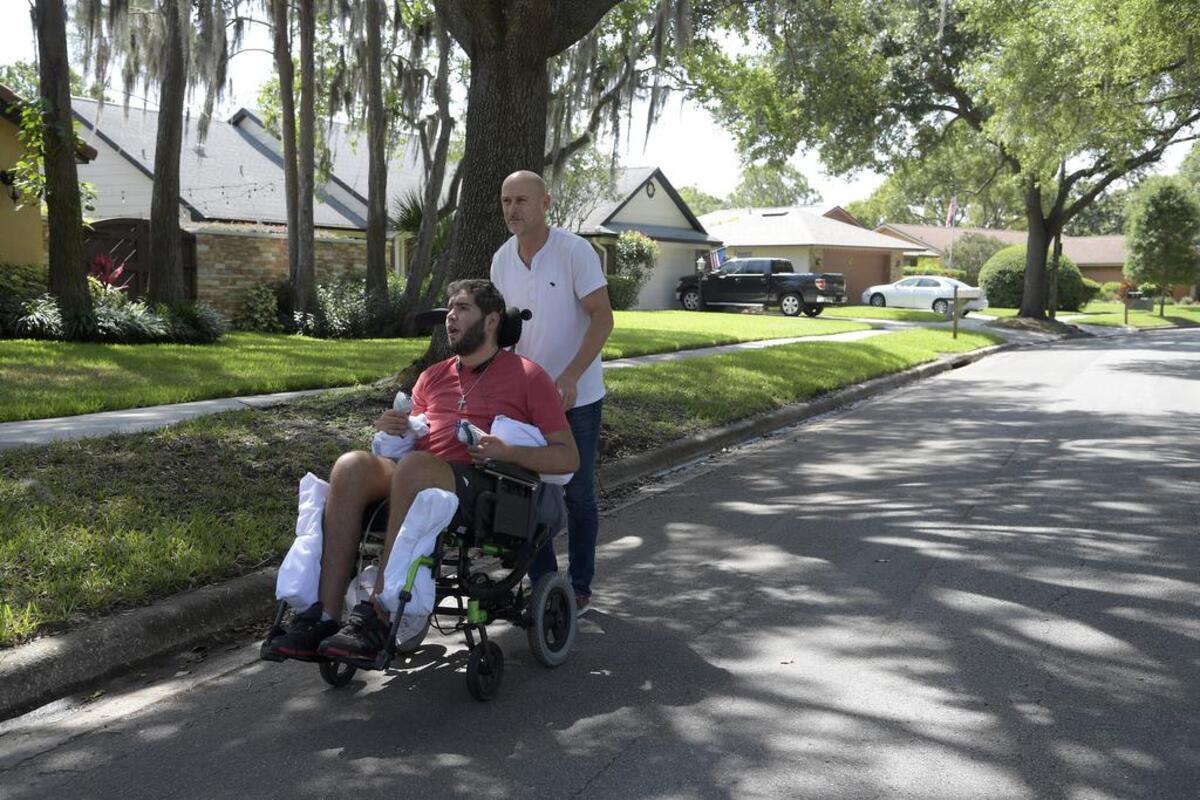 Richard Colón takes his son, Prichard Colón, on a stroll around their neighborhood. The younger Colón remains in a vegetative state after suffering a traumatic brain injury during his bout against Terrel Williams.