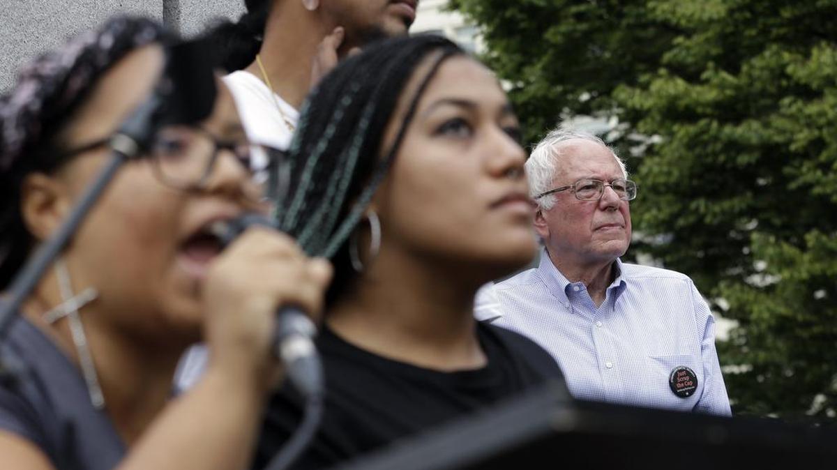 Democratic presidential candidate Sen. Bernie Sanders listens at right as Marissa Johnson speaks at left, accompanied by Mara Jacqueline Willaford on Saturday, Aug. 8, 2015, as the two women take over the microphone at a rally in downtown Seattle. The women, co-founders of the Seattle chapter of Black Lives Matter, took over the microphone moments after Sanders began speaking and refused to relinquish it.