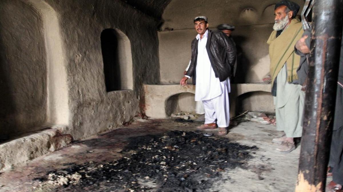 Men stand next to blood stains and charred remains inside a home where witnesses say Afghans were killed by a U.S. soldier in Panjwai, Kandahar province south of Kabul, Afghanistan in 2012
