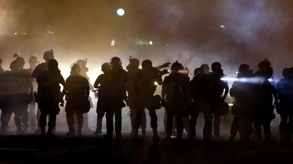
Police walk through a cloud of smoke as they clash with protesters in Ferguson, Mo., on Aug. 13, 2014.The one year anniversary of the shooting of Michael Brown, which sparked months of nationwide protests and launched the "Black Lives Matter" movement, is Aug. 9, 2015. 
