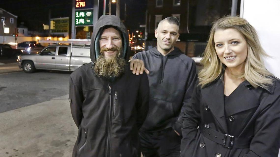 In this Nov. 17, 2017, photo, Johnny Bobbitt Jr., left, Kate McClure, right, and McClure’s boyfriend, Mark D’Amico, pose at a CITGO station in Philadelphia. When McClure ran out of gas, Bobbitt, who is homeless, gave his last $20 to buy gas for her.