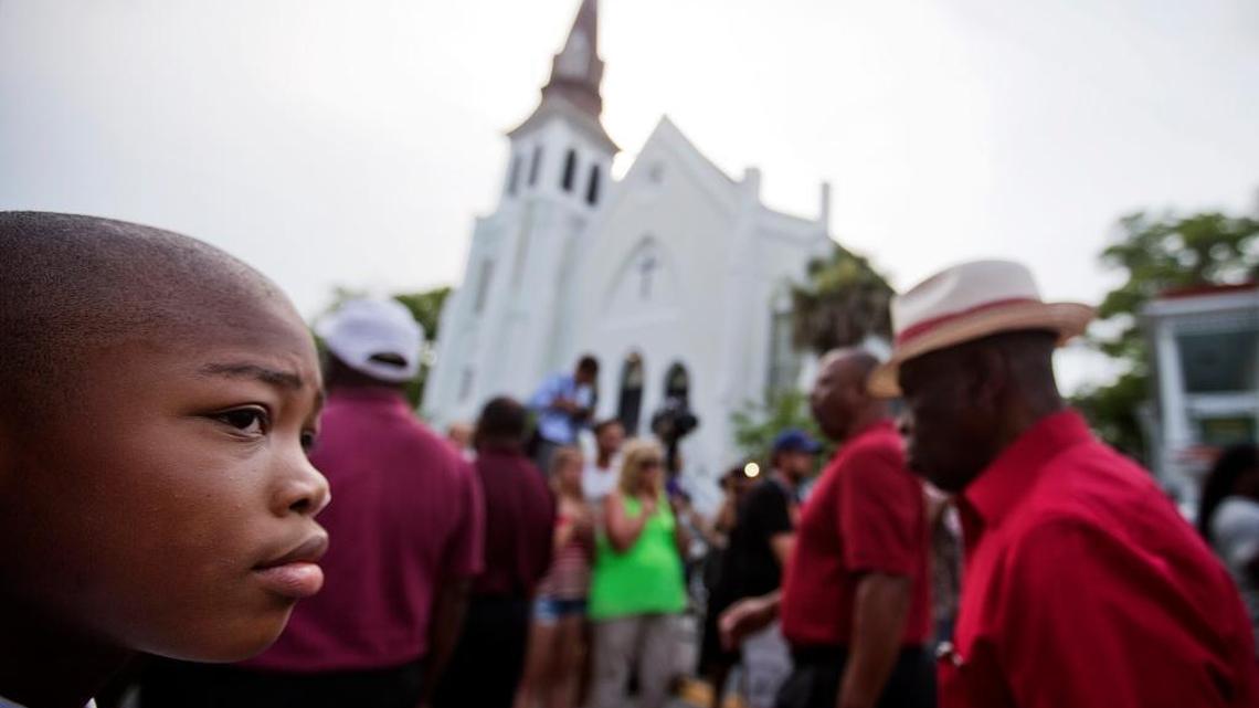 Malik McCarthan, 11, of Hardeeville, S.C., watches as a group passes by singing as the wake for Sen. Clementa Pinckney, one of the nine killed in last week's mass shooting, takes place inside Emanuel AME Church, seen in the background, June 25, 2015, in Charleston, S.C.