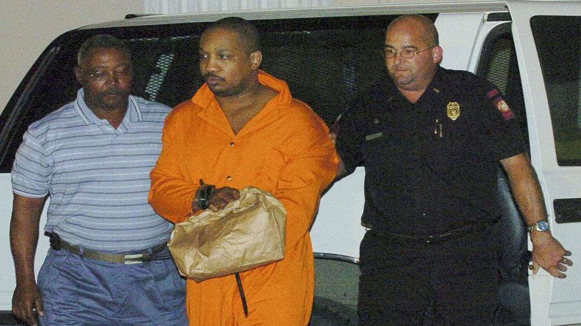 In this Oct. 14, 2004, file photo, Derrick Todd Lee, center, is escorted from a vehicle at Louisiana State Penitentiary at Angola, La. Lee, who was convicted of killing two women and was sentenced to death for the second killing, has died at a hospital.