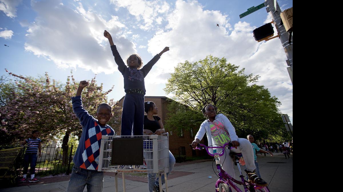 
Children cheer as demonstrators march the day after charges were announced against the police officers involved in Freddie Gray's death, Saturday, May 2, 2015, in Baltimore. 
