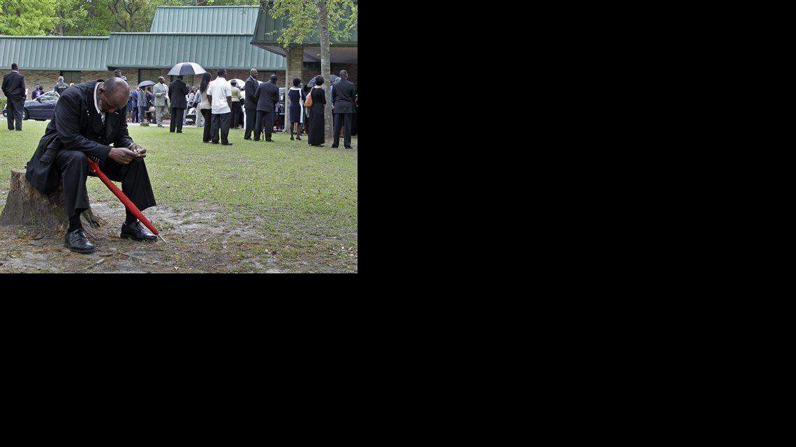 
Eddie Bryan sits on a stump outside the World Outreach Revival Deliverance Ministries Christian Center before the funeral service in Summerville, S.C., Saturday, April 11, 2015 for Walter Scott.
