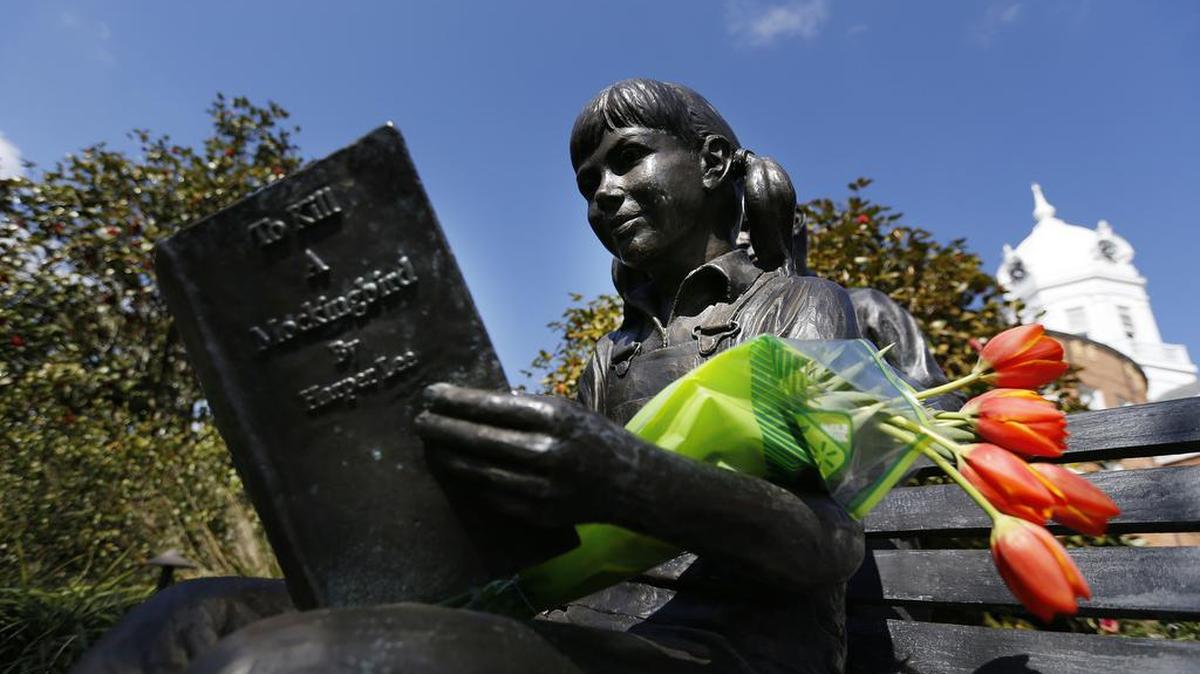 Flowers are placed on a statue of a girl reading Harper Lee's "To Kill a Mockingbird," in memory of Lee, who died Feb. 19, 2016, in Monroeville, Ala.