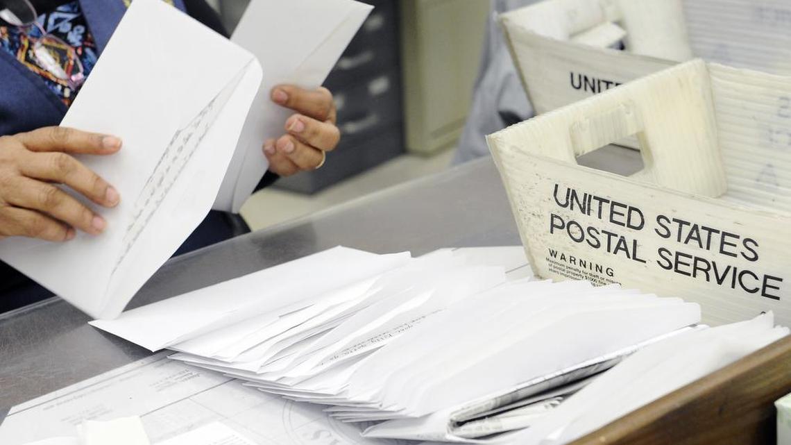 A mail clerk goes through a box of letters.