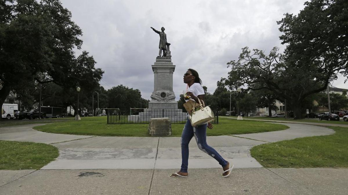 A woman walks past a monument of Jefferson Davis on Jefferson Davis Parkway at Canal Street in New Orleans. A federal lawsuit has been filed challenging a New Orleans city decision to remove the statue and three other Confederate monuments.