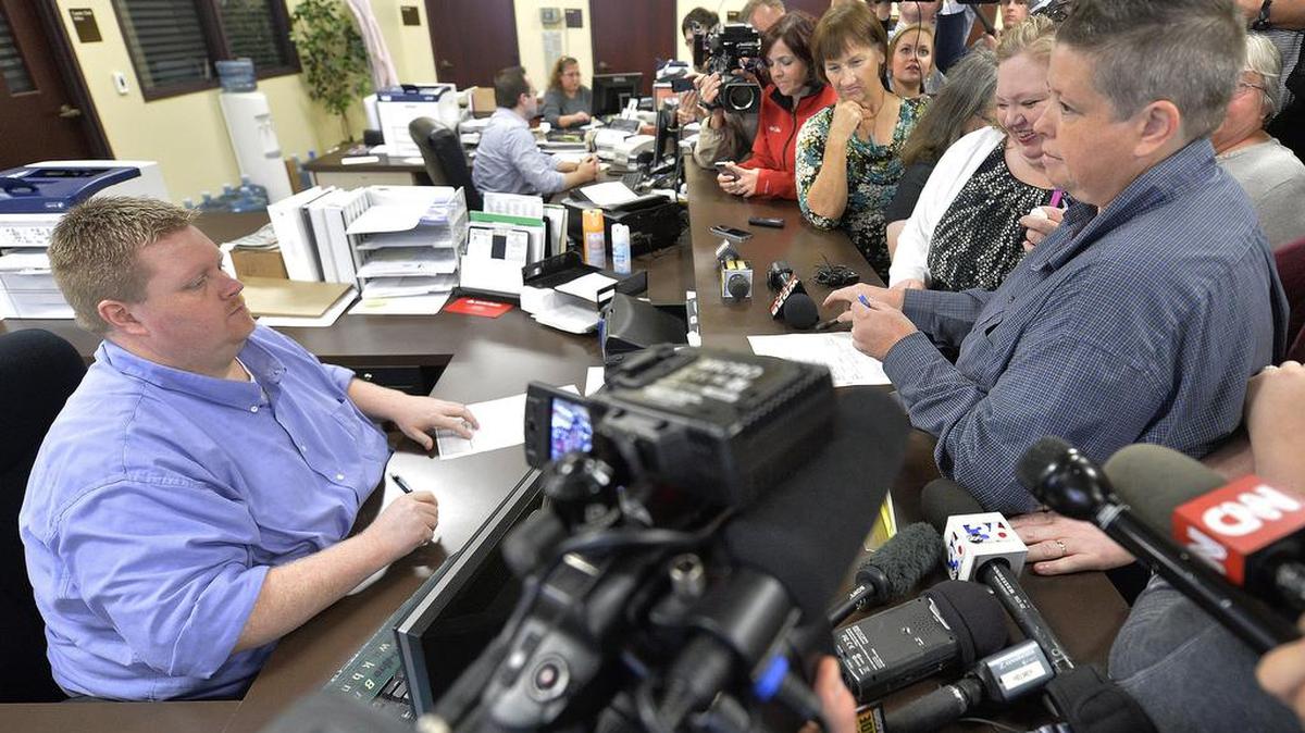 
Rowan County Deputy Clerk Brian Mason, left, asks Shannon Wampler-Collins, right and her partner Carmen Wampler-Collins to double check their marriage license at the Rowan County Judicial Center in Morehead, Ky. on Monday. Mason’s attorney says Davis has altered the licenses and procedures, possibly violating a federal court order.
