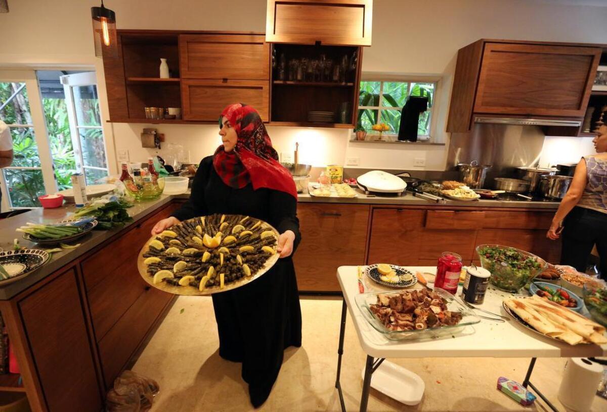 Syrian refugee Kholoud Al Shareef carries a tray of yaprak through a Coral Gables kitchen for the April Syrian Supper Club.