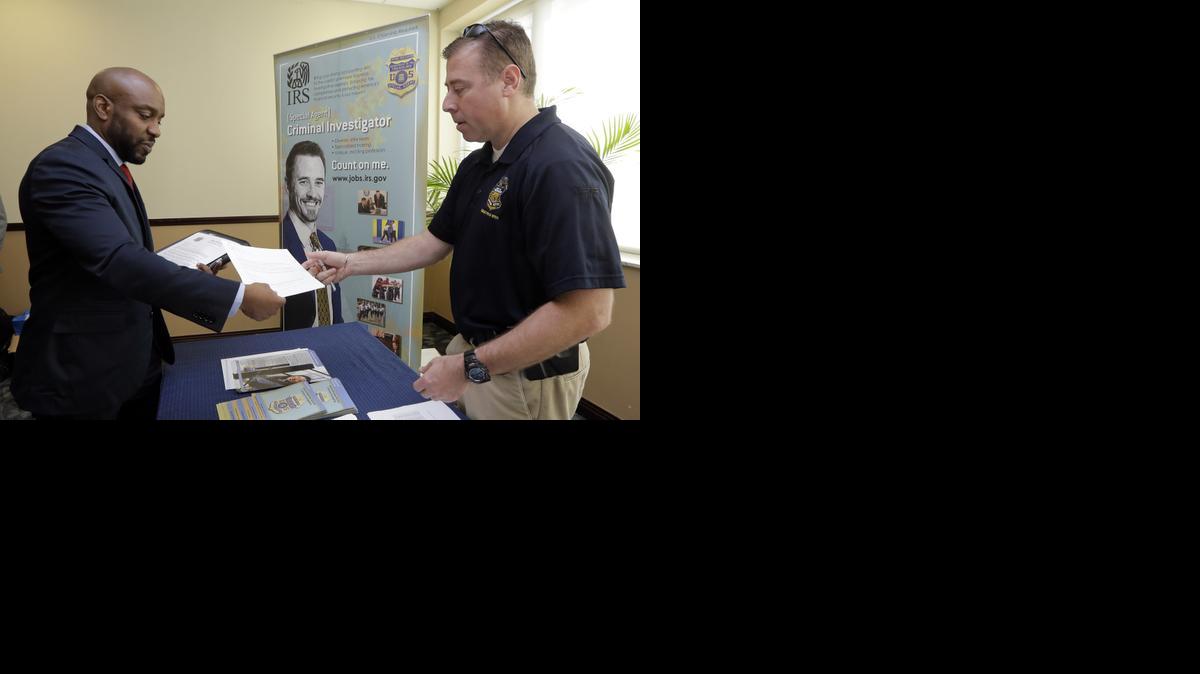 
In this Feb. 6, 2015 photo, U.S. Marine Corps Veteran Arlington Robertson, of Fort Lauderdale, left, hands his resume to an Internal Revenue Service Special Agent, at the annual Veterans Career and Resource Fair in Miami. The Labor Department releases employment data for February on Friday, March 6, 2015. 
