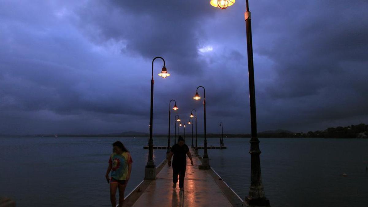 
A couple walks on a pier under cloudy skies as Tropical Storm Erika approaches the island in Naguabo, Puerto Rico, Thursday, Aug. 27, 2015. Erika was expected to move near Puerto Rico and the Virgin Islands on Thursday and be near or just north of the Dominican Republic on Friday as it heads toward Florida early next week, possibly as a hurricane. 
