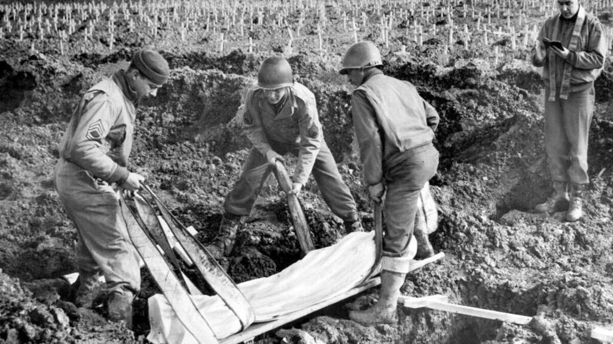 Maj. John B. Day, right, an Army chaplain from Springfield, Ill., conducts burial services for an unidentified American soldier in the largest military cemetery on the western front at Henri Chappell in Belgium in an undated photo. Lowering the body into the grave are T/Sgt. A.H. Herberts, of Chester, Ill; S/Sgt. Vito Mastrangelo,of Visalia, Calif.; and Pfc. Irvin W. Kestner, of Oakland, Calif., left to right. Crosses in the background marked the graves of several thousand other American dead. Undated photo.