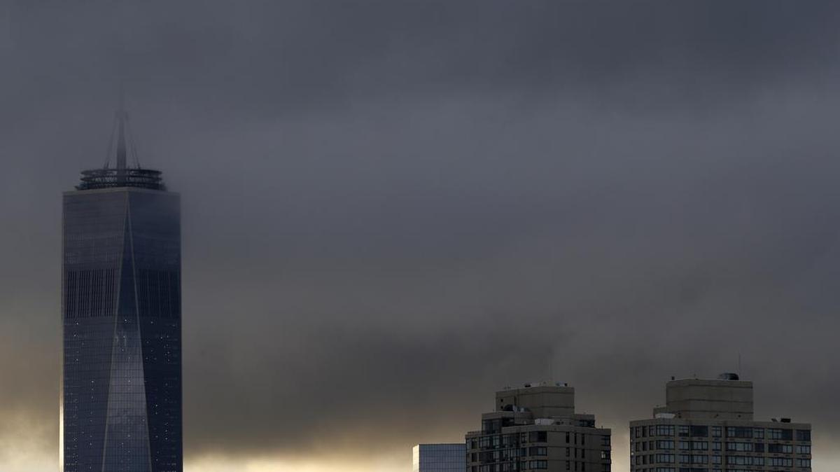 
Low clouds surround the top of the One World Trade Center tower, left, at sunrise during the 14th anniversary of the terrorist attacks, Friday, Sept. 11, 2015, seen from The Heights neighborhood of Jersey City, N.J. 

