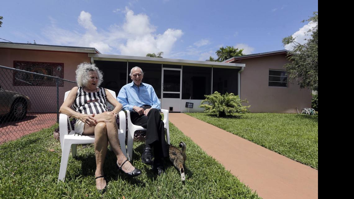 In this May 11, 2015 photo, Al Karp, right, and wife Saundra, pose in front of their home in North Miami Beach, Fla. The Karps, along with their son, Larry, perform old standards locally as the Karp Family band to ease stress and help raise money to save their home from foreclosure.
