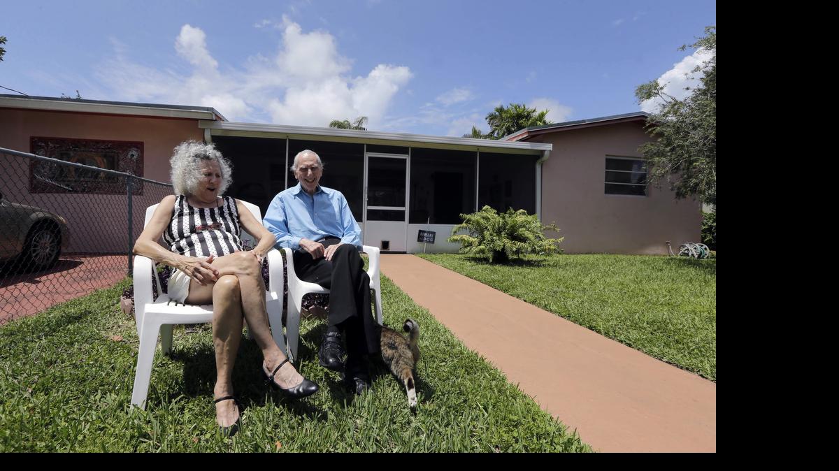 In this May 11, 2015 photo, Al Karp, right, and wife Saundra, pose in front of their home in North Miami Beach, Fla. The Karps, along with their son, Larry, perform old standards locally as the Karp Family band to ease stress and help raise money to save their home from foreclosure.