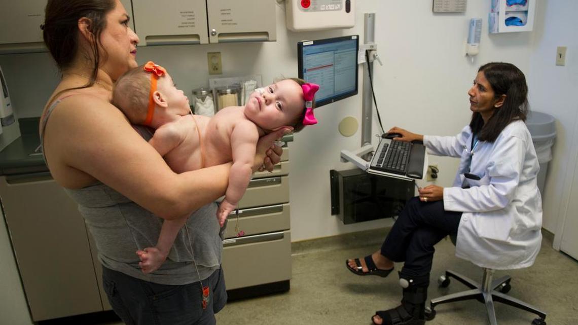 
Aida Sandoval holds conjoined twins Eva and Erika as she talks with Sutter Roseville pediatrics doctor, Eswari Prakasam during a well-baby visit on May 27. The twins share a liver, some intestinal tract and much of their reproductive systems.
