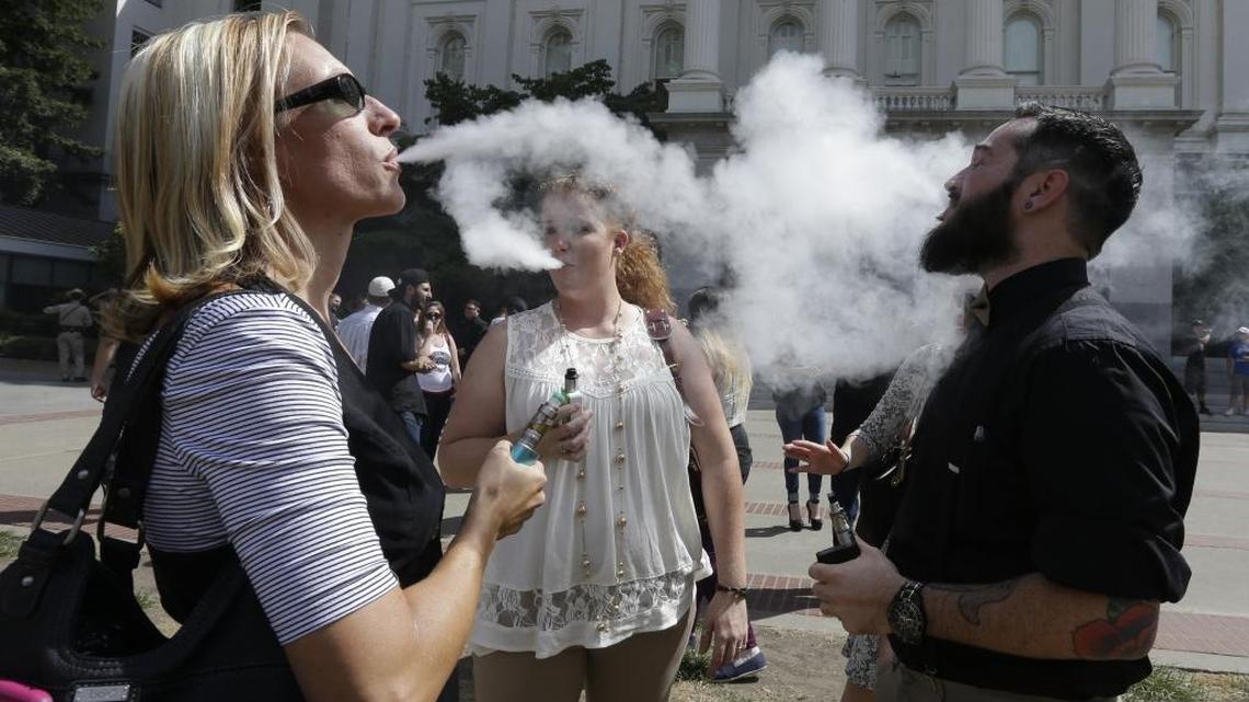 Kari Hess, left, co-owner of Nor Cal Vape in Redding, Calif., celebrates with Jackie Voisione, center, and Michael Ventura, right, an e-liquid manufacturer from San Diego, after a bill to regulate e-cigarettes stalled in an Assembly committee on July 8, 2015. On Wednesday, however, Gov. Jerry Brown signed laws that will place tight restrictions on e-cigarettes.