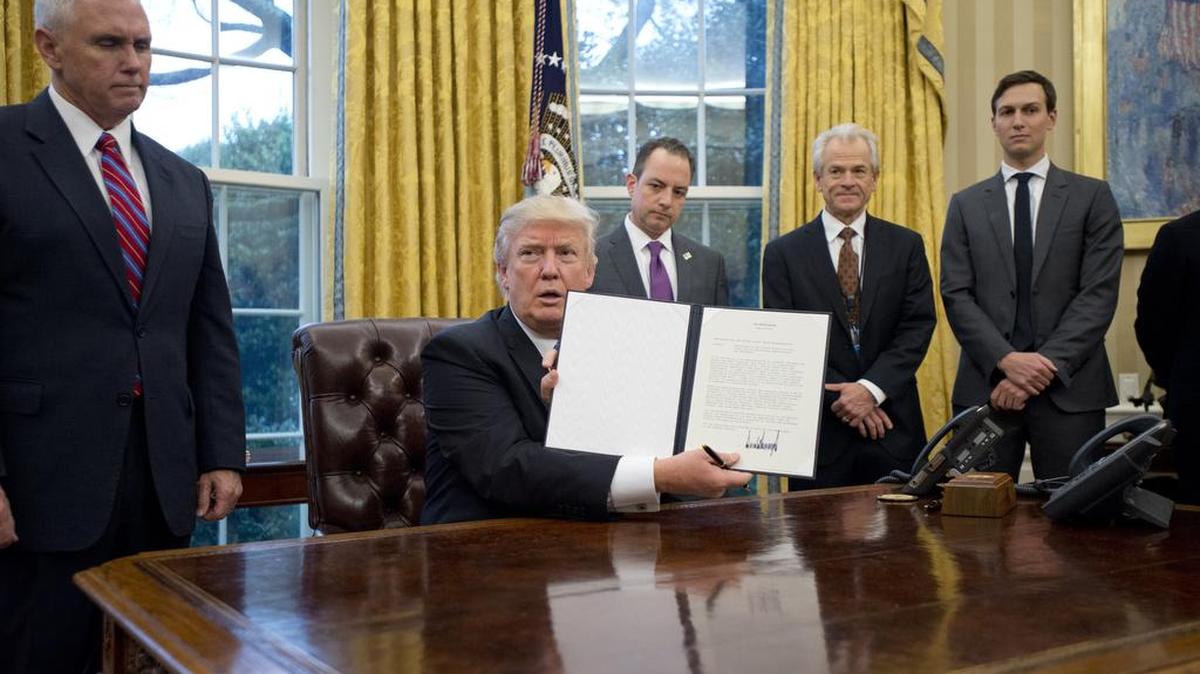 President Trump shows the executive order withdrawing the U.S. from the Trans-Pacific Partnership after signing it on Monday, Jan. 23, 2017 in the Oval Office of the White House in Washington, D.C. Standing behind the him, from left, U.S. Vice President Mike Pence; White House Chief of Staff Reince Preibus; Peter Navarro, director of the National Trade Council; and Jared Kushner, senior advisor.