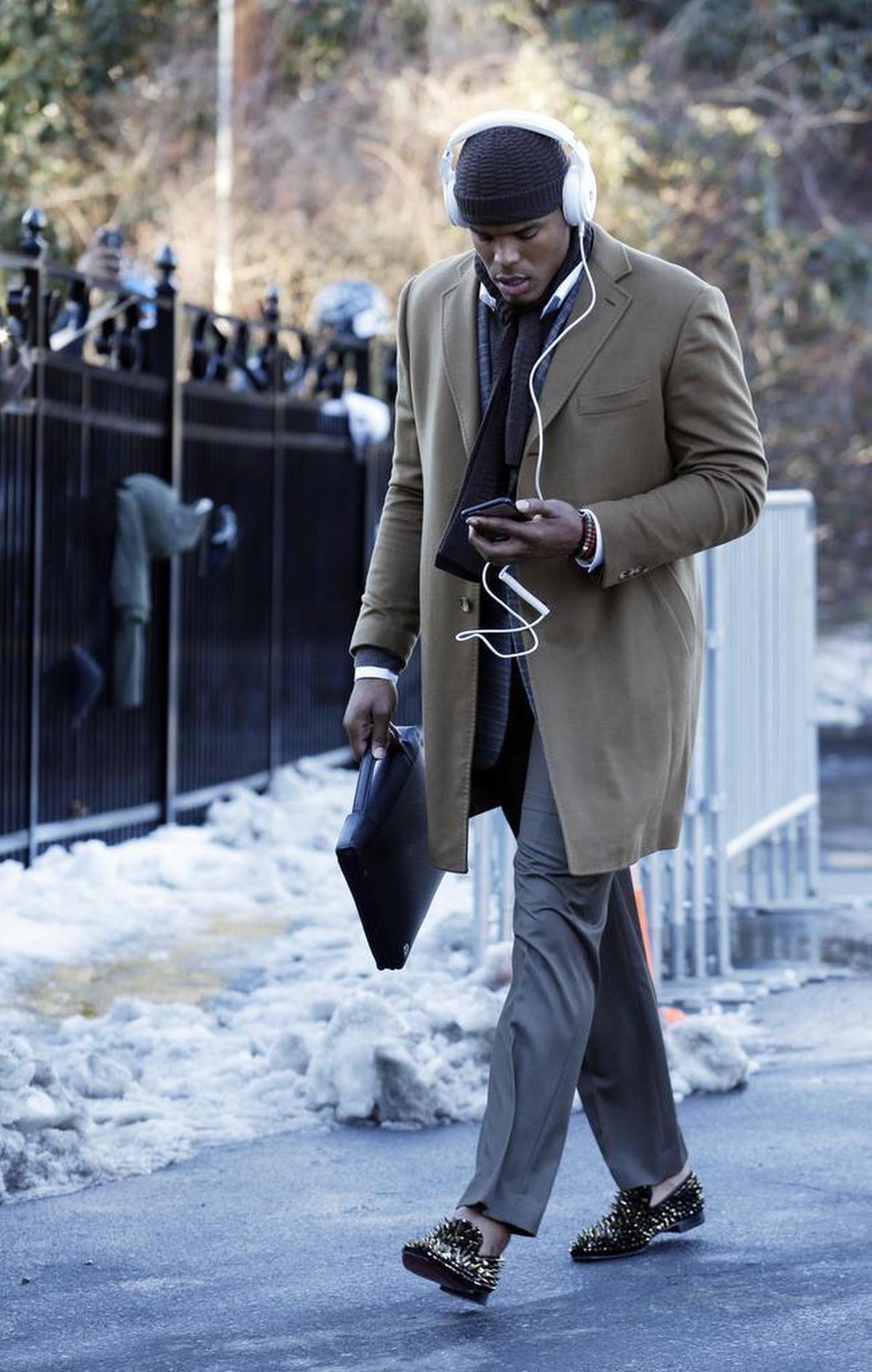 Cam Newton is the MVP of layering. In this photo, taken as he arrived for the Jan. 24 NFC Championship game against Arizona, Cam is rocking gray slacks, a plaid sports jacket and a khaki colored overcoat (willing to bet there’s also a collared shirt and sweater under that jacket), with a scarf, knit hat and a small leather attache. Please, please pay special attention to studded loafers.