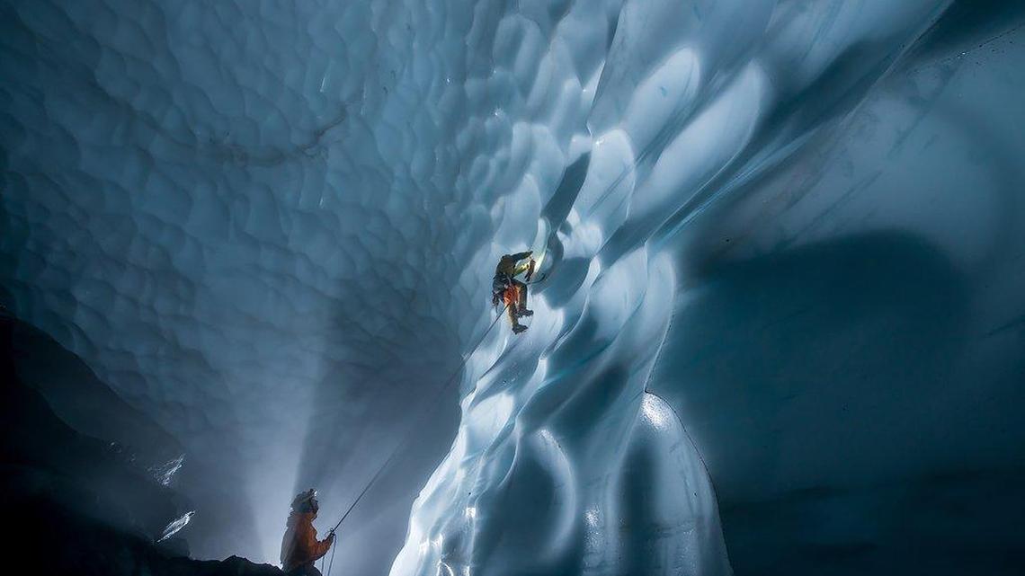 Eddy Cartaya, belayed by James Frystak, climbs the ice wall of a chamber to place ablation markers in the ice that will allow measuring of melting over time.