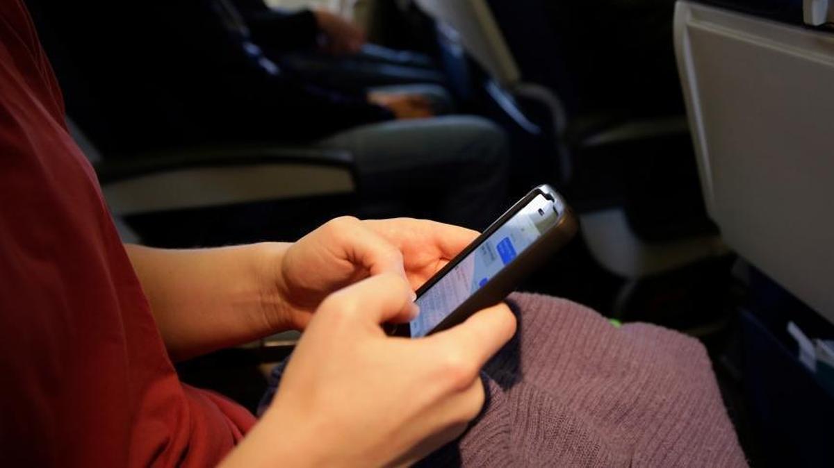 A passenger checks her cell phone before a flight.