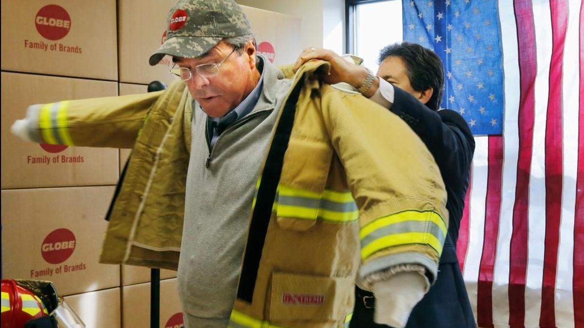 Republican presidential candidate Jeb Bush puts on a fire jacket given to him during a campaign stop at Globe Manufacturing in Pittsfield, New Hampshire, on Thursday, Feb. 4. 2016. For now, Bush still has the backing of most Republicans in Florida’s congressional delegation.