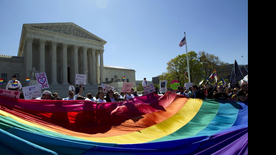 
In this April 28, 2015, file photo, demonstrators stand in front of a rainbow flag of the Supreme Court in Washington, as the court was set to hear historic arguments in cases that could make same-sex marriage the law of the land. Gay and lesbian couples could face legal chaos if the Supreme Court rules against same-sex marriage in the next few weeks. Same-sex weddings could come to a halt in many states, depending on a confusing mix of lower-court decisions and the sometimes-contradictory views of state and local officials. Among the 36 states in which same-sex couples can now marry are 20 in which federal judges invoked the Constitution to strike down marriage bans. 
