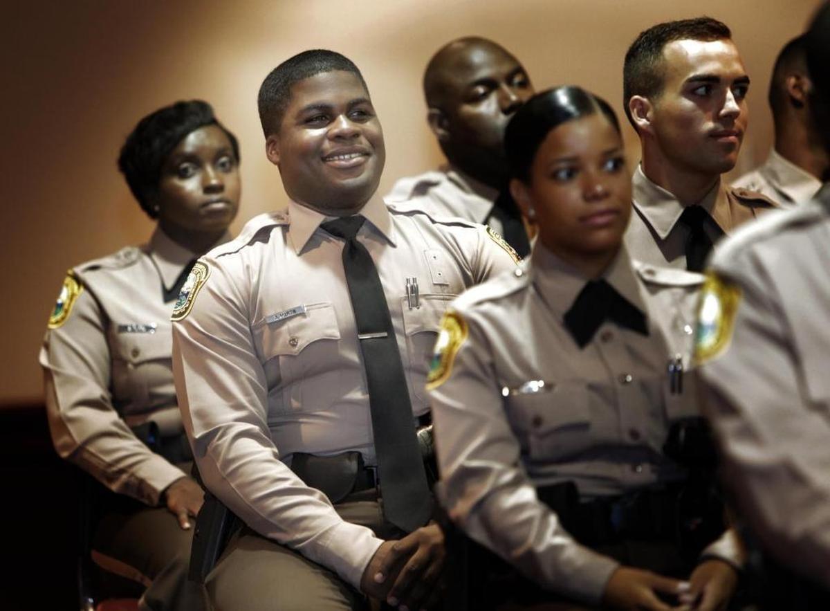 Andre Martin, second from left, sits with fellow Police Academy Graduates during the graduation ceremony. Thursday morning, Andre Martin, a 26-year-old martial arts expert with a fiance and a child, was part of the new graduating class of Miami-Dade police.