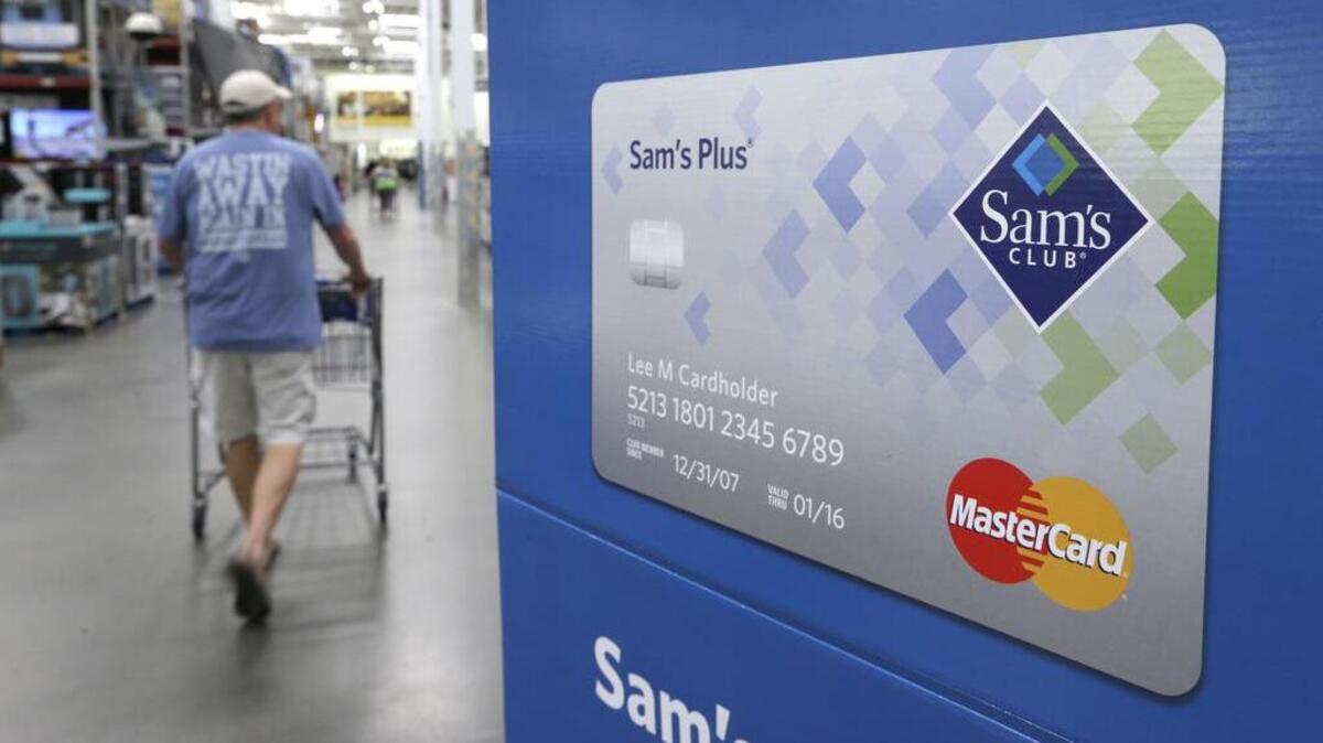 In this Thursday, June 4, 2015, file photo, a customer walks past a sign promoting the Sam’s Club Mastercard credit card at a Sam’s Club store store in Bentonville, Ark. Saving money on holiday purchases now by opening a store credit card could cost you later in credit score points.